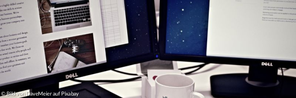 Arbeitsplatz mit 2 Bildschirmen, Tastatur und Kaffeetasse